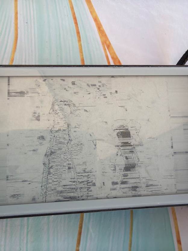Photo of the e-paper panel showing a barely visible, washed-out sketch-like image with scattered horizontal black dashes
